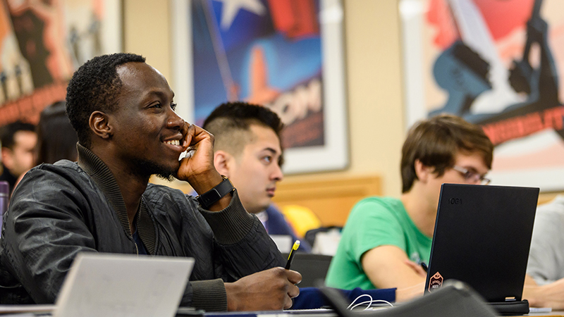 Black, male student smiling and listening in class.